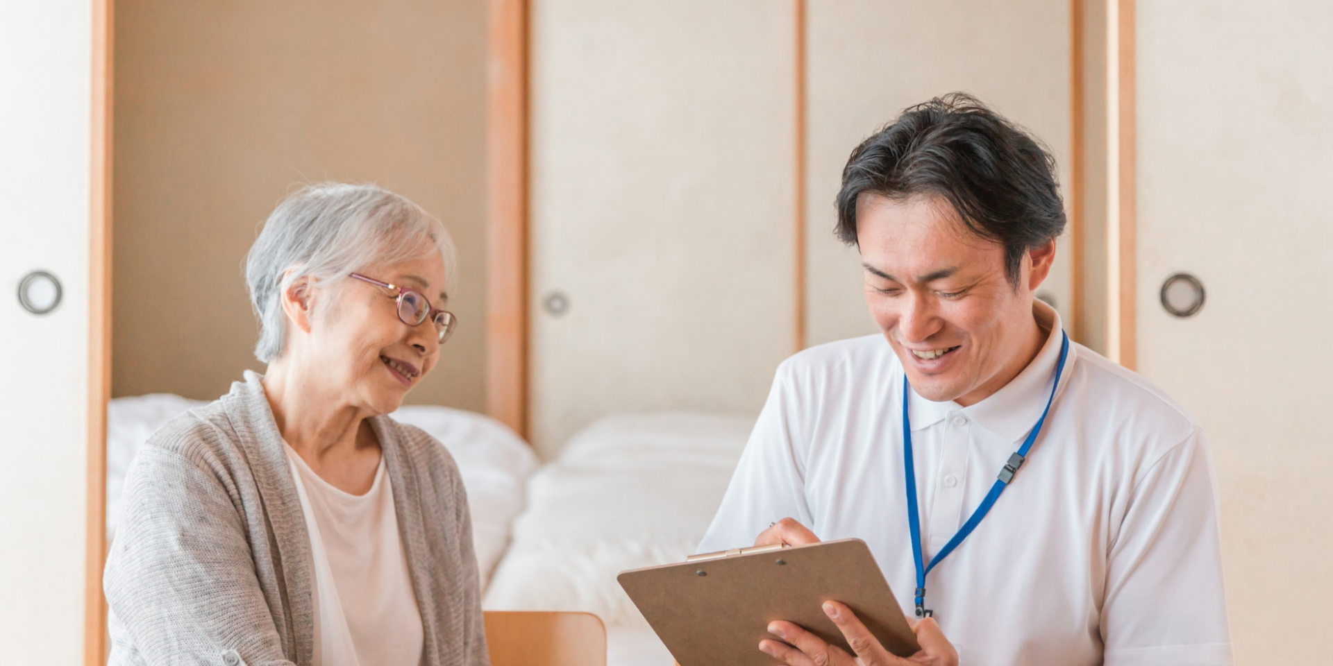 在宅で看護を受ける高齢女性と施設員男性の写真