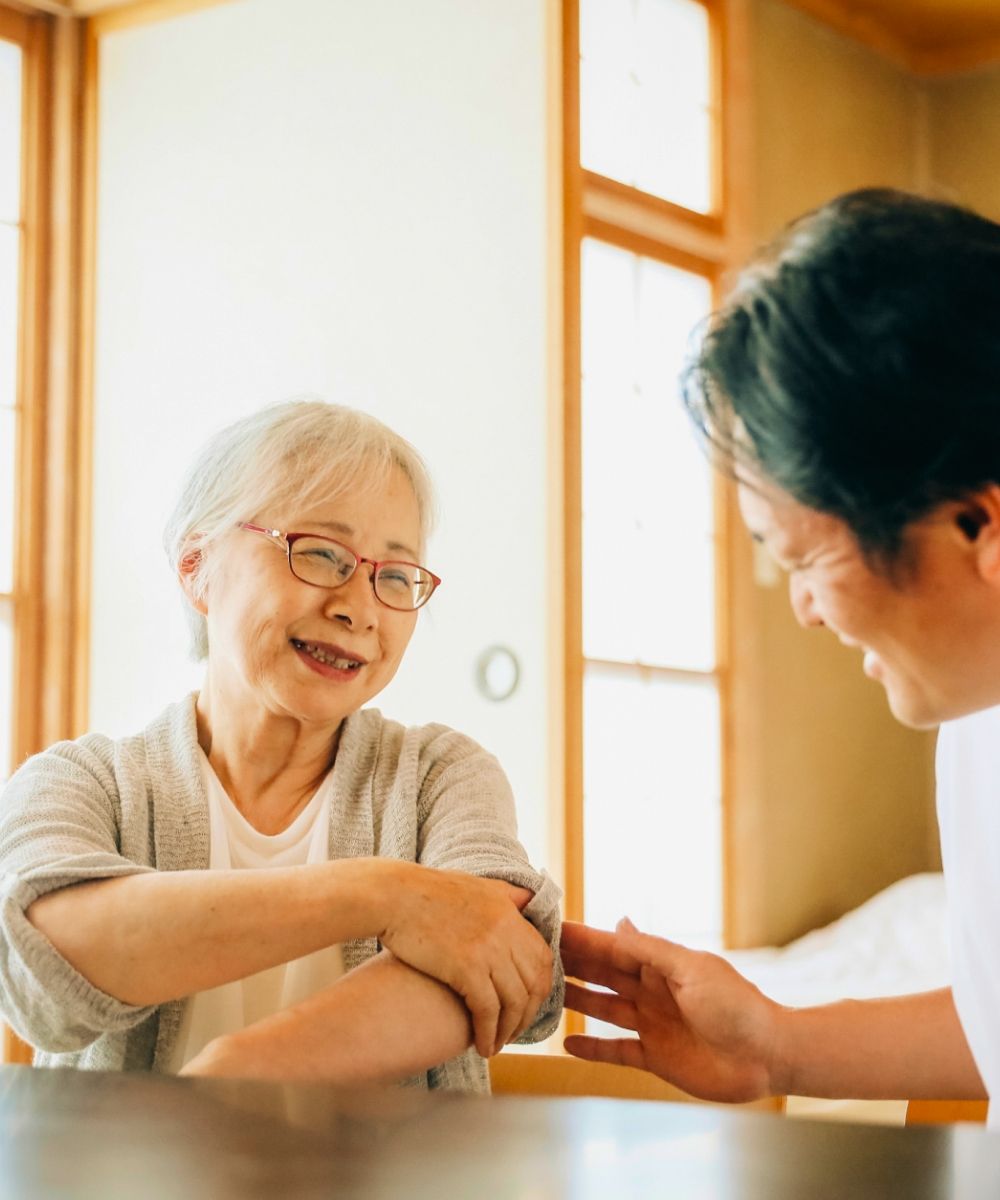 在宅で看護を受ける高齢女性と施設員男性の写真